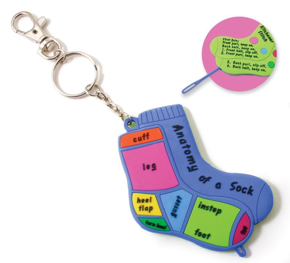The Sock Doctor Knitting Tool by Bryson Distributing, Inc. is a colorful sock-shaped keychain labeled with parts—cuff, leg, heel flap, gusset, instep, foot, toe—and features a chart explaining knitting terms like kitchener stitch.