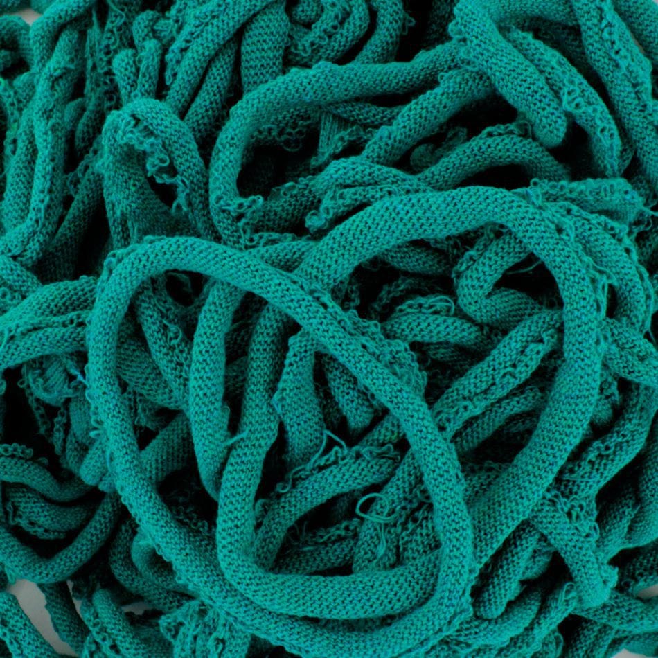 A collection of Harrisville Potholder Loops in teal from Friendly Loom, featuring knitted or woven fabric strips that evoke the traditional loom style with a textured and intricate pattern of loops and twists.