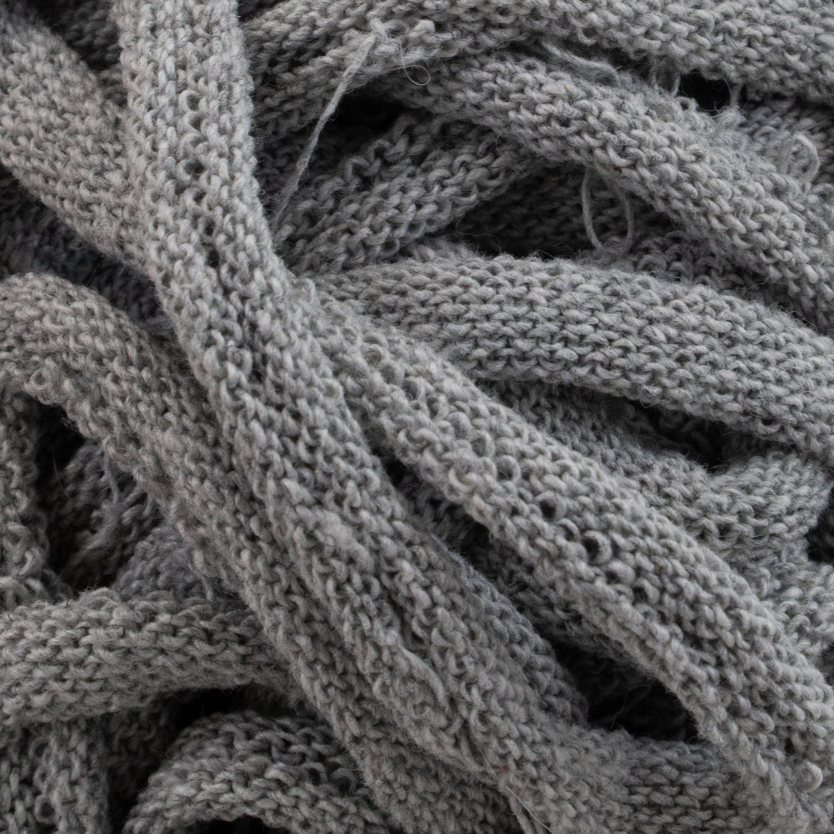 Close-up image of a bundle of thick, intertwined loops reminiscent of traditional loom techniques from the Harrisville Potholder Loops - Traditional Size by Friendly Loom. The loops have a soft, woolly texture, with visible fibers and strands overlapping in various directions for a textured and layered appearance.