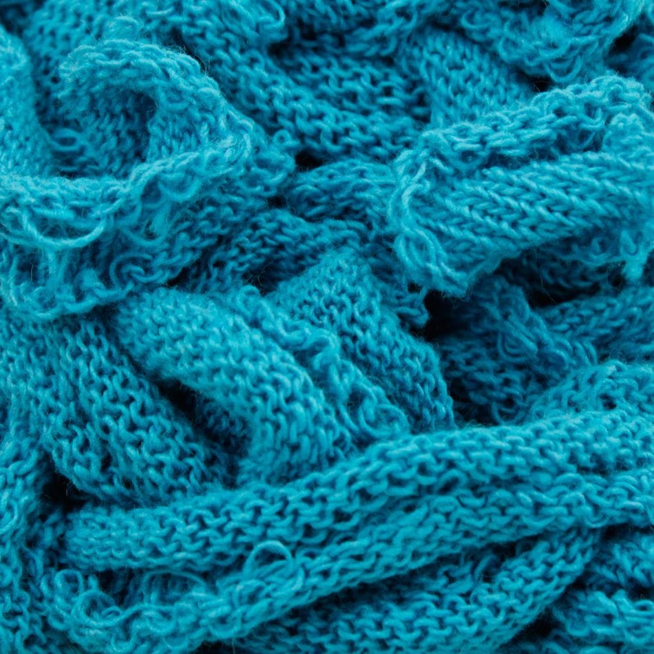 Close-up of a pile of tangled, Harrisville Potholder Loops in turquoise from Friendly Loom, reminiscent of intricate cotton loops on a traditional loom, showcasing its detailed textures.