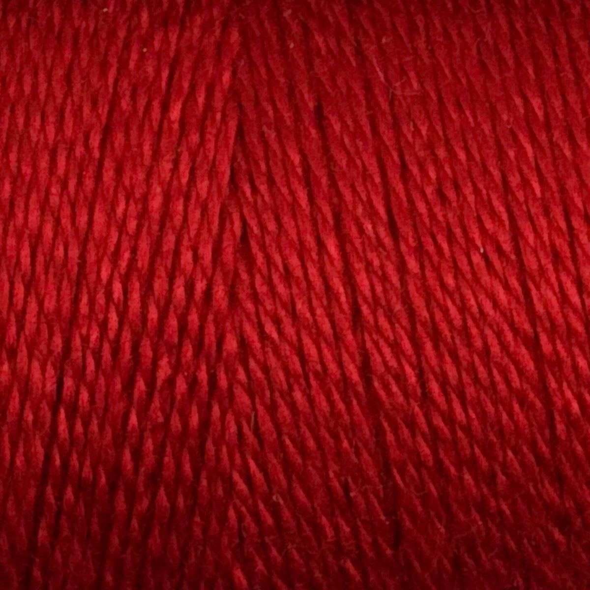 Close-up of tightly twisted Maurice Brassard 8/2 Tencel Yarn | Mini-cone in red, highlighting its smooth, shiny texture and vibrant color—ideal for weaving projects.